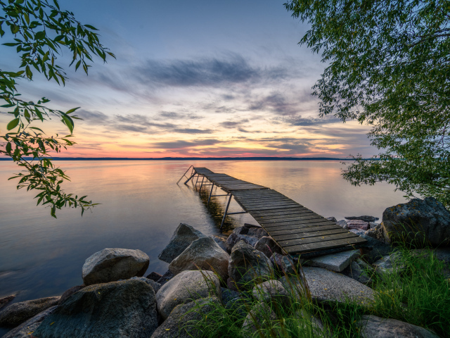 Старый деревянный пирс у озера на закате