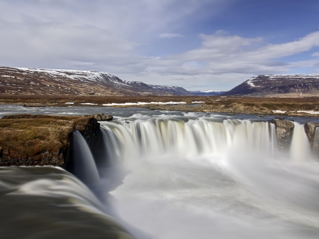 Водопад стекает вниз на фоне гор