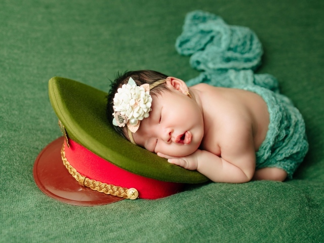 Маленький ребенок спит на военной фуражке