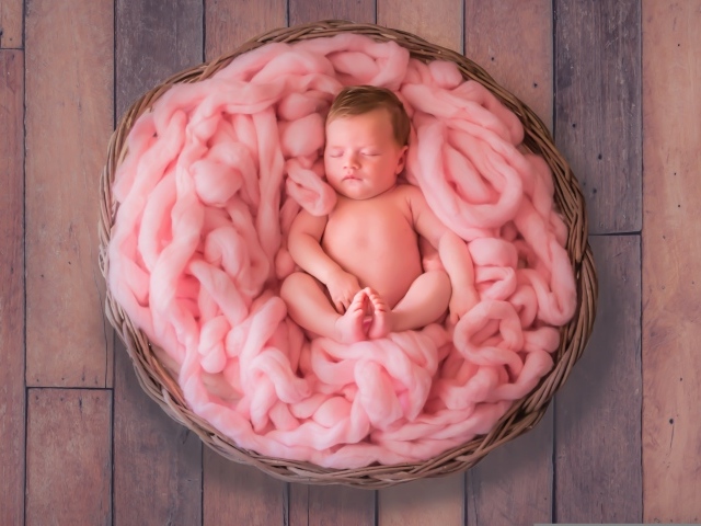 Ребенок спит в корзине с розовым покрывалом