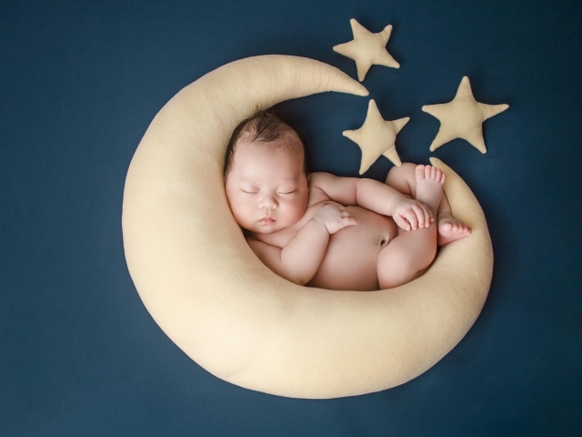 Ребенок спит на игрушечном месяце