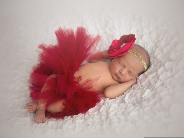 Красивая пышная красная юбка и бант на спящей малышке