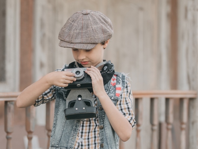 Мальчик в кепке с фотоаппаратом в руках