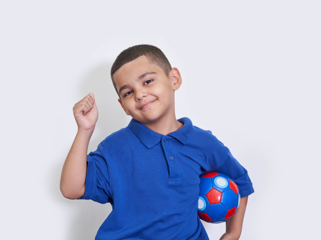 Мальчик футболист с мячом  на сером фоне 