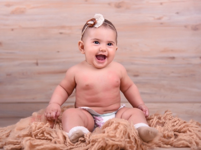 Милый улыбающийся ребенок на фоне деревянной стены