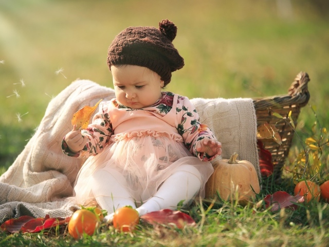 Смешная маленькая девочка сидит на траве с тыквой