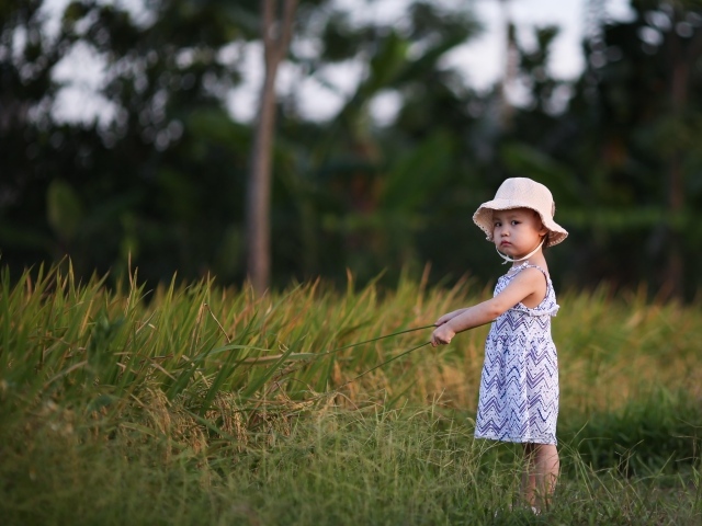 Девочка в платье стоит на траве 