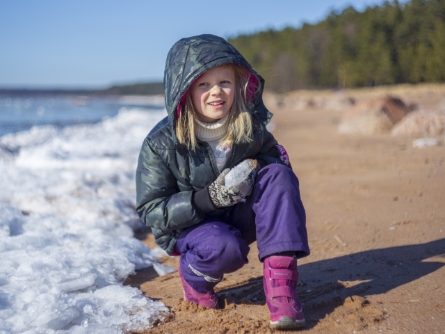 Девочка сидит у замерзшего озера 
