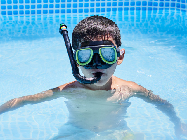 Маленький мальчик в маске в бассейне