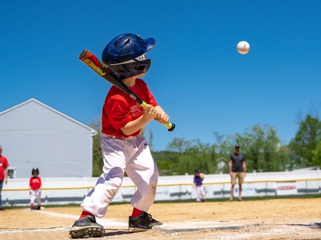 Маленький мальчик играет в бейсбол 