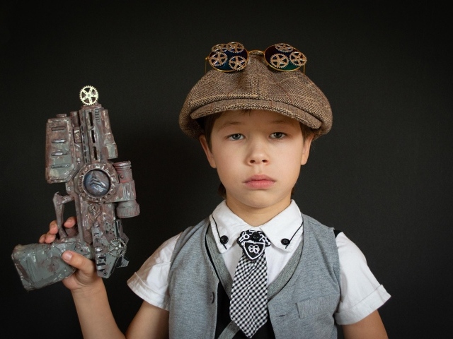 Маленький мальчик с игрушечным пистолетом на черном фоне