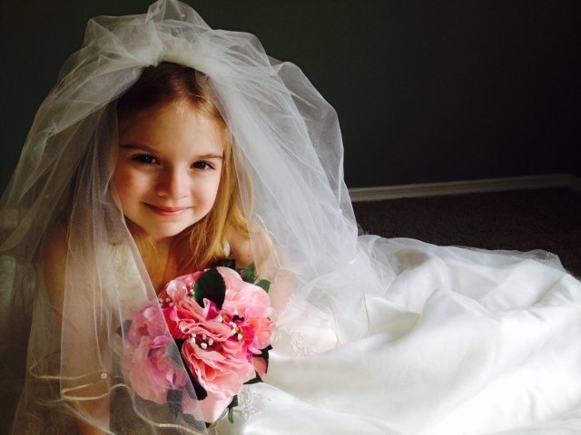 Маленькая девочка в костюме невесты с букетом