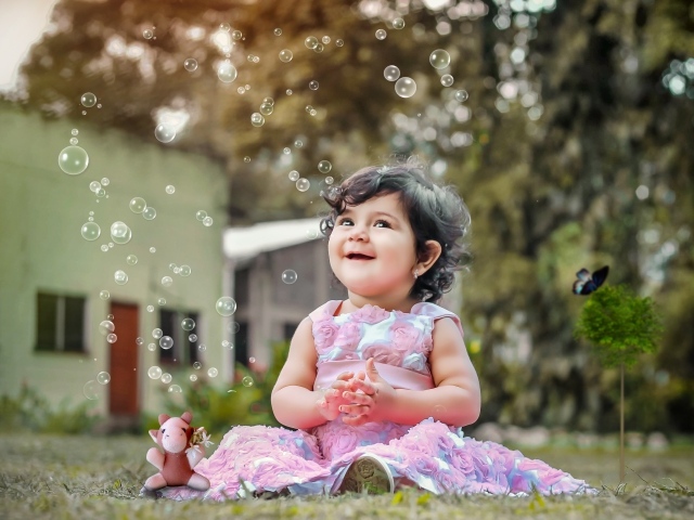 Маленькая девочка радуется мыльным пузырям