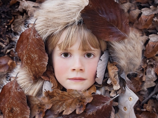 Маленькая девочка лежит в опавшей листве