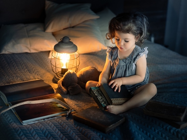 Маленькая девочка читает книги на кровати