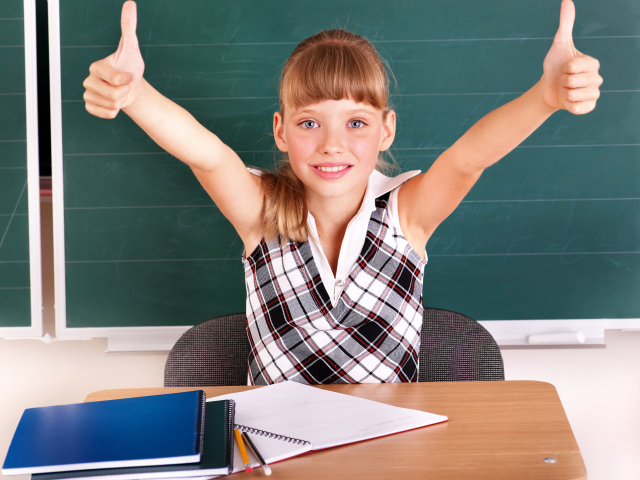 Маленькая девочка школьница в классе за партой 