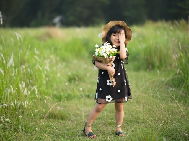 Маленькая девочка с букетом цветов на зеленой траве