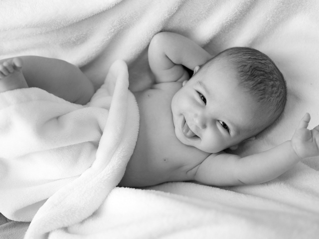 Маленький улыбающийся ребенок в белом покрывале