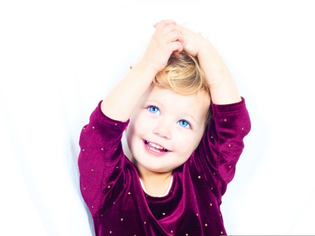 Маленькая улыбающаяся голубоглазая девочка на белом фоне