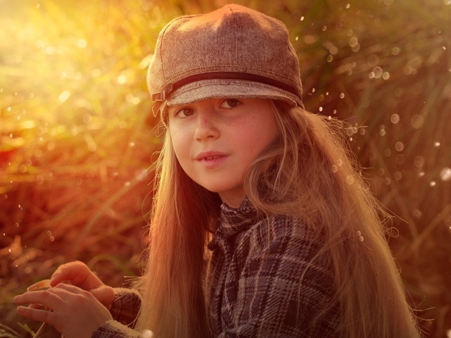 Длинноволосая девочка в кепке в лучах солнца