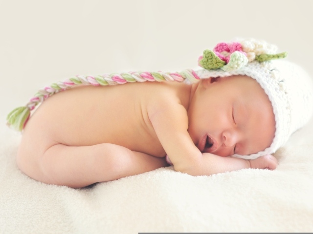 Новорожденная девочка спит в шапке