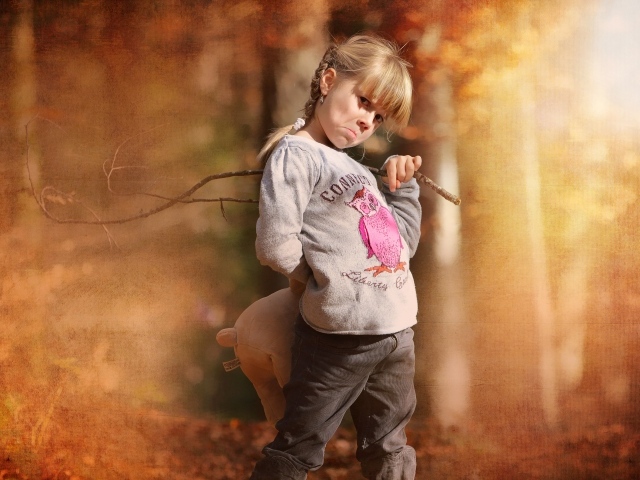 Обиженная девочка с игрушкой и палкой в лесу 