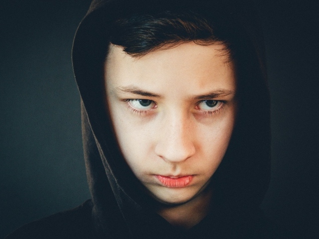 Серьезный мальчик в черном капюшоне