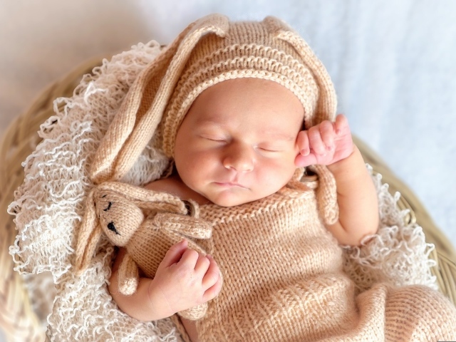 Спящий грудной ребенок в вязаном костюме