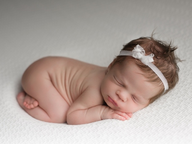 Спящая новорожденная девочка с ободком на голове