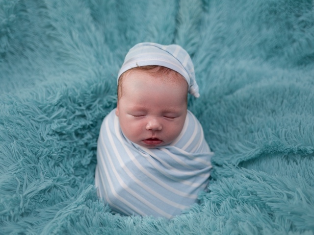 Спящий новорожденный малыш на голубом покрывале 