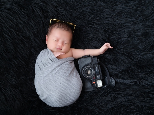 Спящий новорожденный малыш с фотоаппаратом