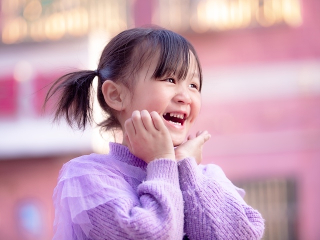 Улыбающаяся маленькая девочка азиатка в свитере