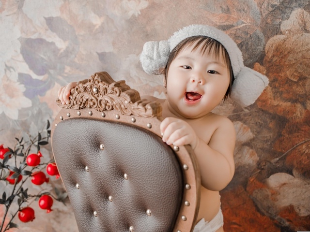 Улыбающийся ребенок азиат стоит у кресла