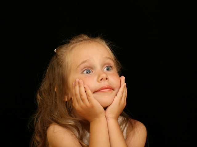 Удивленная маленькая девочка на черном фоне