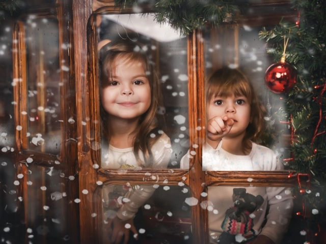 Две маленькие девочки сидят у окна на Рождество