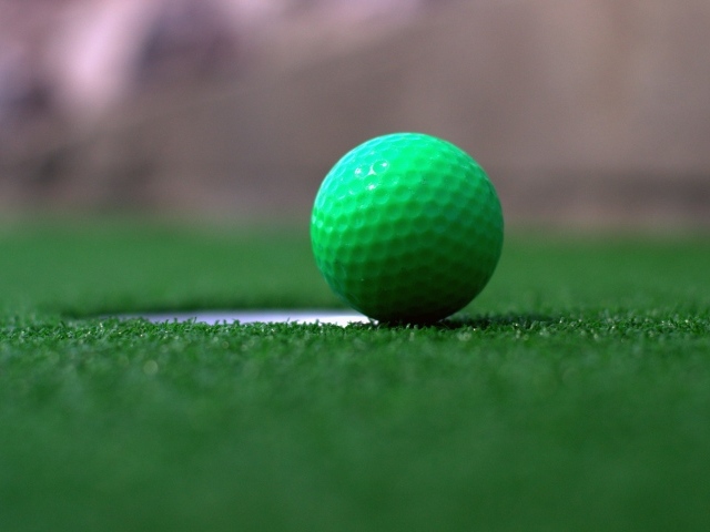 Зеленый мяч для игры в гольф на траве