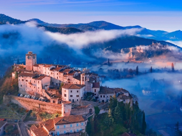 Вид на город на горе в тумане, Италия