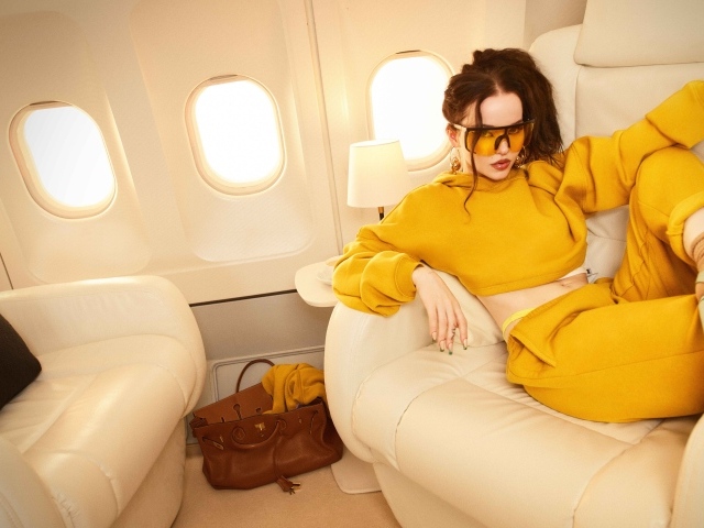 Актриса Дав Кэмерон в желтом костюме в самолете