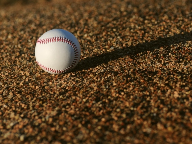 Бейсбольный мяч в лучах солнца на асфальте