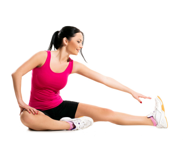 Красивая брюнетка делает упражнения на белом фоне