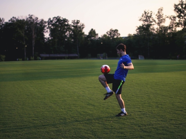 Мужчина футболист с мячом на поле
