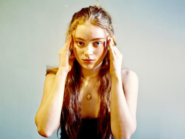 Рыжеволосая американская актриса Сэди Синк на сером фоне