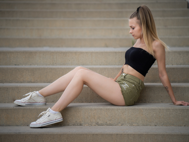 Стройная спортивная девушка сидит на ступеньках