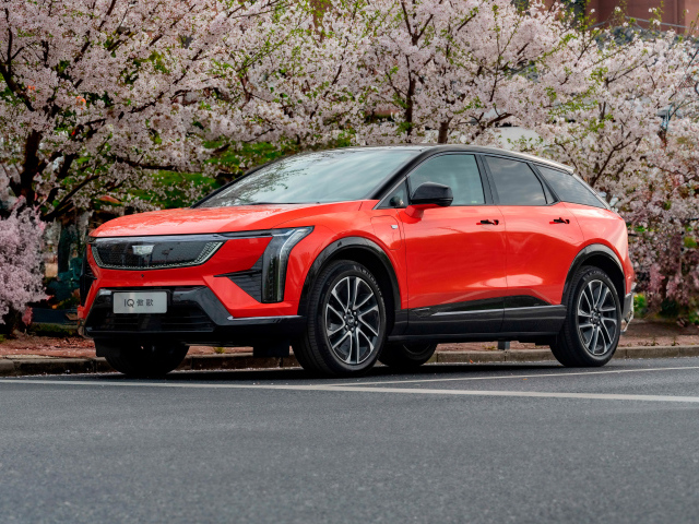 Красный Cadillac Optiq Sport 2024 года у цветущих деревьев