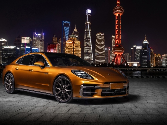 Золотистый автомобиль Porsche Panamera Turbo E-Hybrid 2024 года на фоне города
