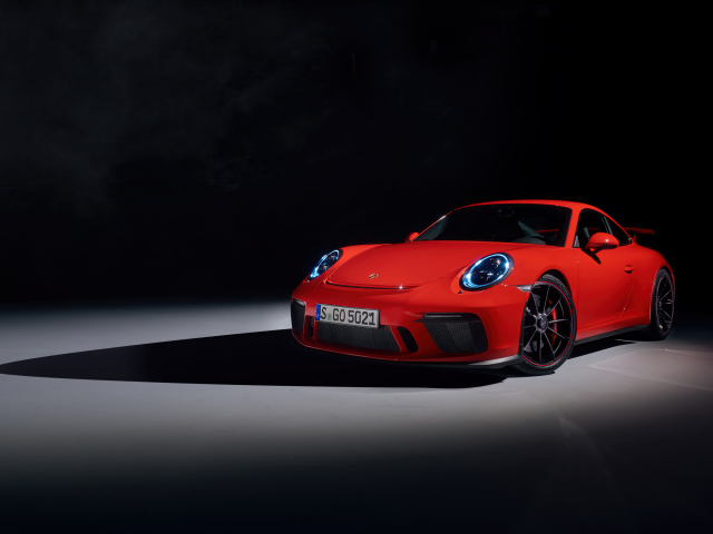 Красный автомобиль Porsche 911 GT3 на черном фоне