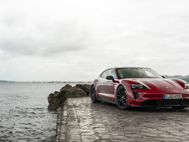 Красный автомобиль Porsche Taycan  у воды