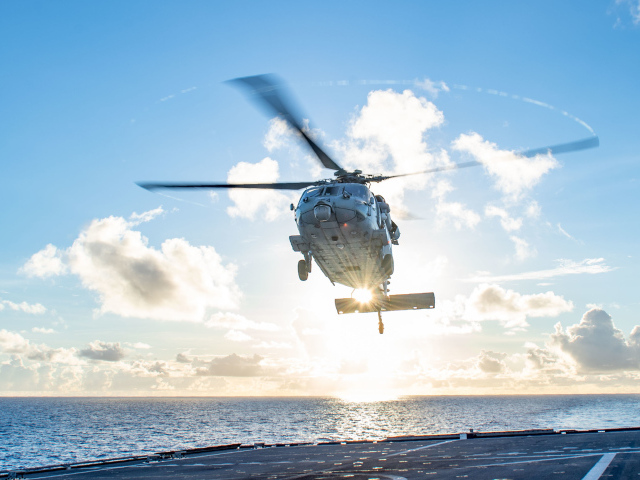Военный вертолет приземляется на корабль в море