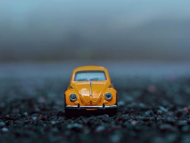 Маленькая игрушечная машинка стоит на асфальте