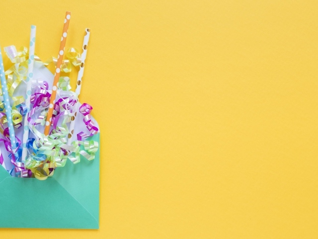 Конверт с трубочками и лентами на желтом фоне